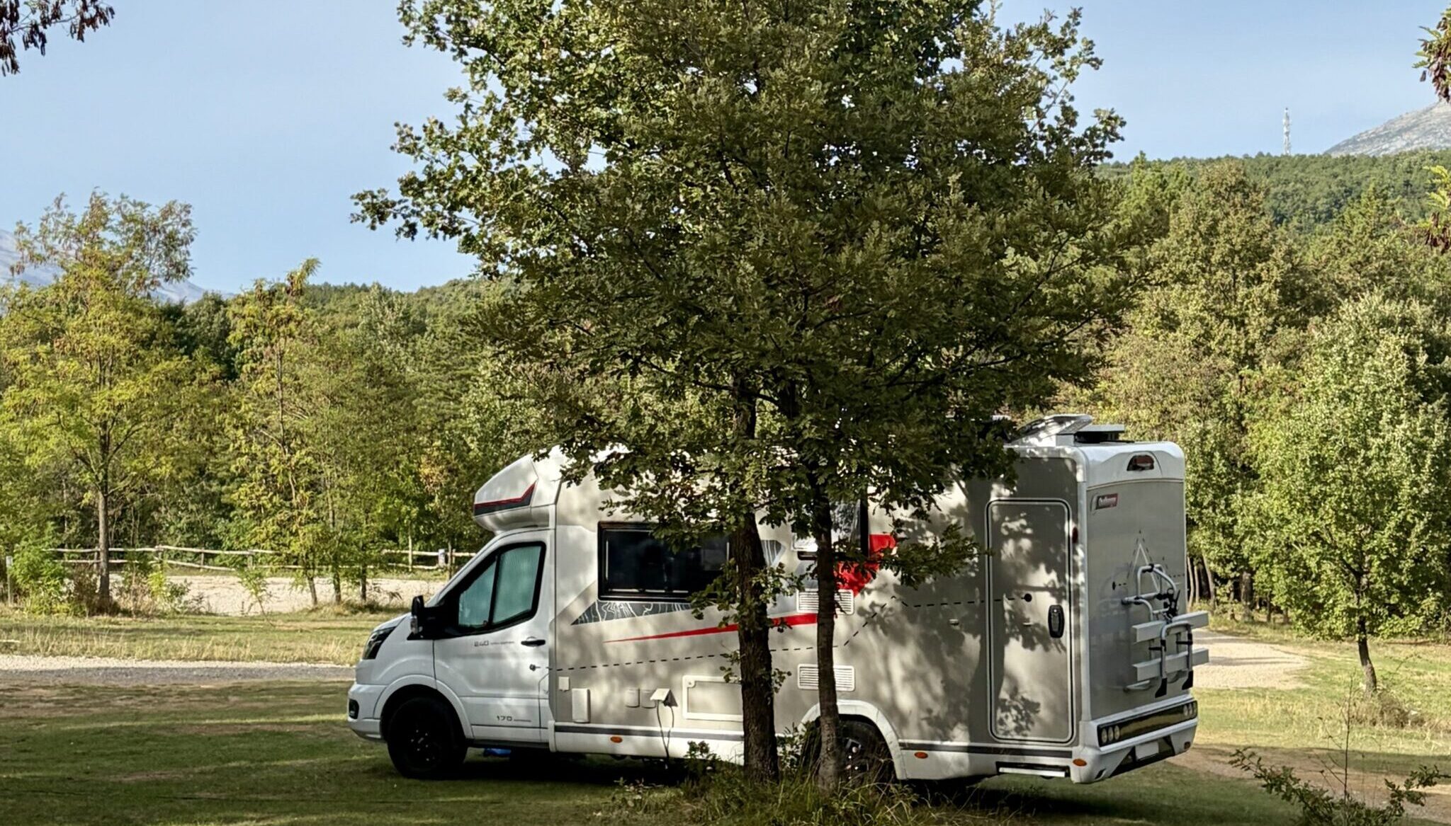 Wohnmobil auf einem naturbelassenen Stellplatz unter einem Baum bei Camping Peruca